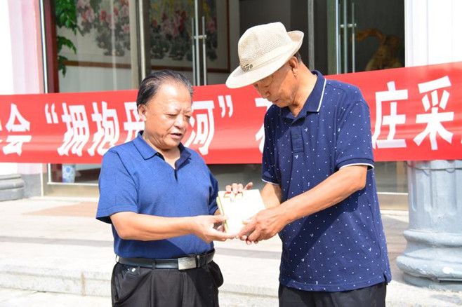 市作协副主席郑海涛(左)向石门山庄主人许永志赠送自己出版的作品